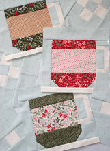 Load image into Gallery viewer, "Cocoa Party" Christmas row quilt featuring patchwork Santa, peppermint swirls, cocoa mugs, marshmallows, and holly and berry sashing. This Christmas sampler quilt is made with fat eighths of Peppermint Cocoa fabric by Lella Boutique for Moda Fabrics. Download the PDF here!