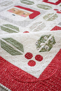 Jolly Holiday Christmas quilt by Vanessa Goertzen of Lella Boutique. Christmas medallion quilt design featuring traditionally piece Santa, holly berries and leaves, and scrappy gifts. Jelly Roll friendly! Fabric is Christmas Eve by Lella Boutique for Moda Fabrics arriving May 2023.