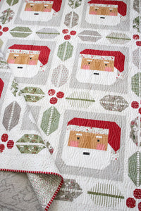 St. Nick Santa quilt by Vanessa Goertzen of Lella Boutique. Traditionally pieced Santa block framed with holly and berry quilt blocks. Make it with a Jelly Roll or Layer Cake. Fabric is Christmas Eve by Lella Boutique for Moda Fabrics.