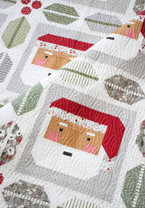 St. Nick Santa quilt by Vanessa Goertzen of Lella Boutique. Traditionally pieced Santa block framed with holly and berry quilt blocks. Make it with a Jelly Roll or Layer Cake. Fabric is Christmas Eve by Lella Boutique for Moda Fabrics.