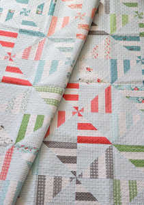 Parade scrappy pinwheel quilt from the book: Jelly Filled - 18 Quilts from 2-1/2" Strips by Vanessa Goertzen of Lella Boutique. Get your autographed copy of the book here! Lots of great jelly roll strip quilts. Fabric is Nest by Lella Boutique for Moda Fabrics.